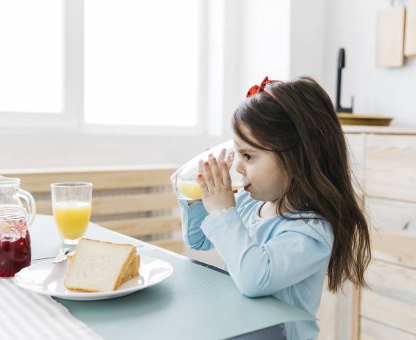 A child holding a sandwich at a table with breakfast items.